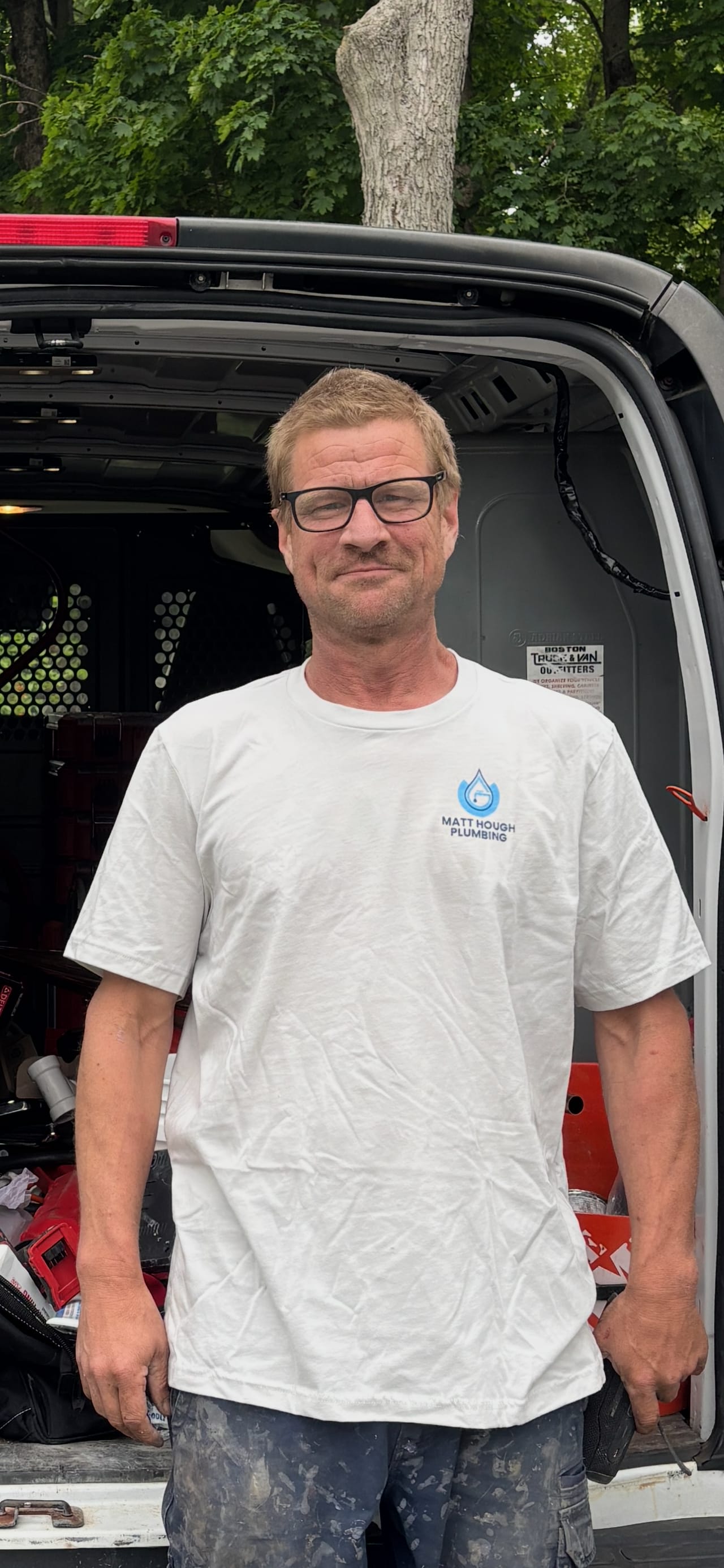 Matt Hough at the open back doors of his work van, wearing a Matt Hough Plumbing shirt